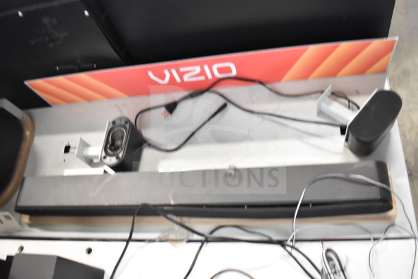 Store display featuring LG soundbar with visible cables and Vizio signage. Includes extra equipment for gaming setup.