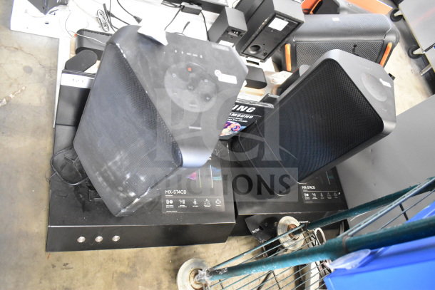 Store display with two Samsung speakers, models MX-ST4CB, with control panels visible, used condition.