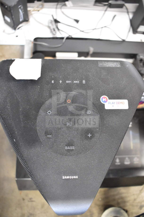 Samsung speaker with control panel, featuring Bluetooth, AUX inputs, and demo play sticker. Store display model.