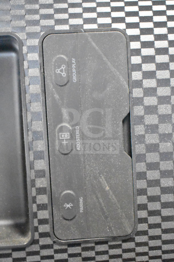 Samsung speaker control panel with buttons for Group Play, Add Stereo, and Pairing on a checkered background.
