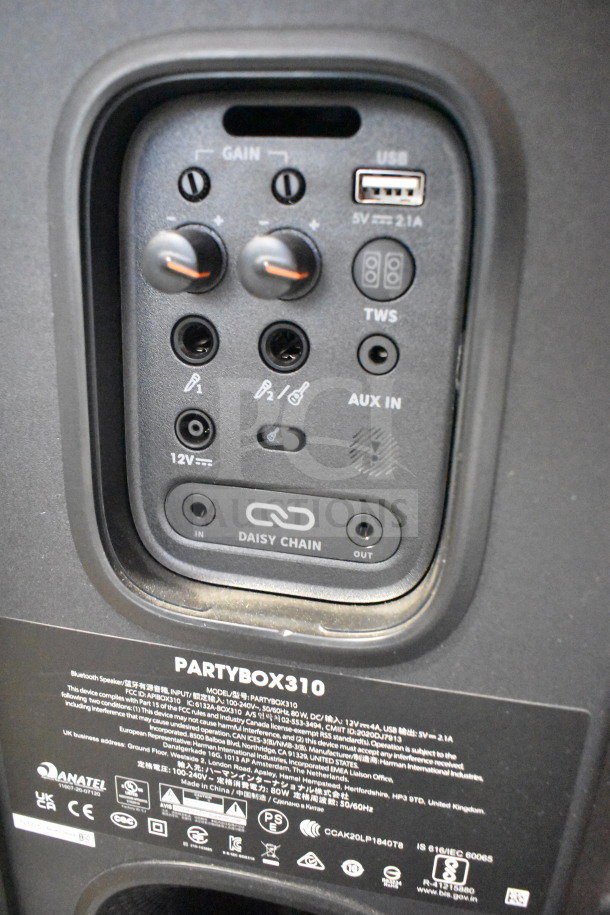 JBL Partybox 310 speaker close-up showing controls and ports, including gain knobs, USB, AUX input, and daisy chain.