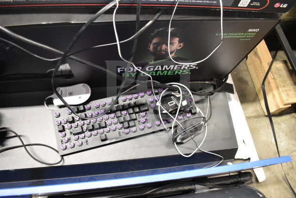 Auction display with keyboard, mouse, and cables. Includes headphones and soundbar. Features "For Gamers" signage.