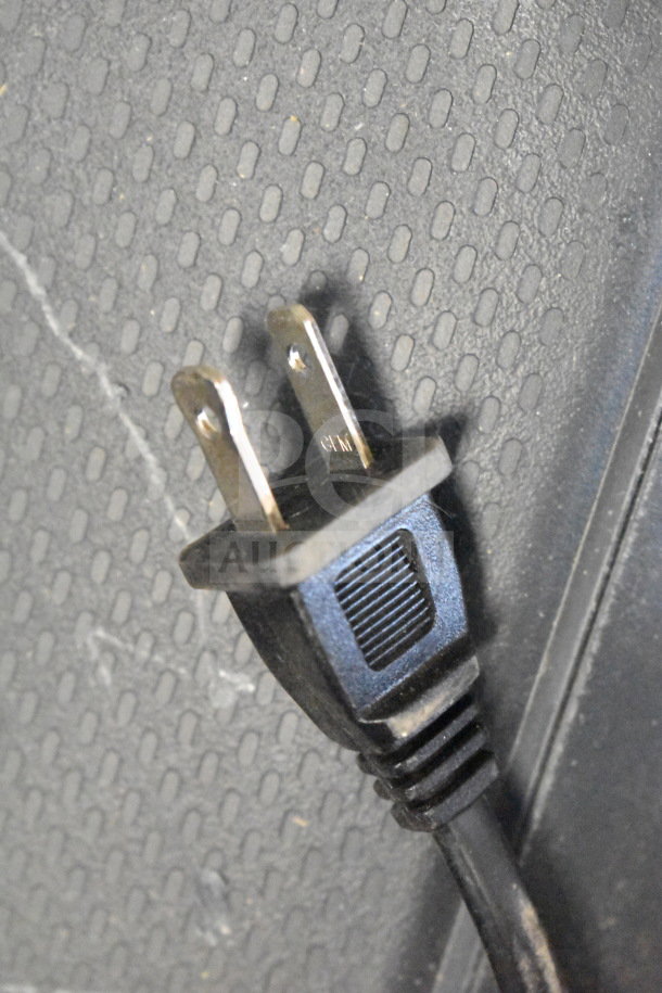 Two-prong plug on textured black surface, possibly related to Onn speaker display item. Condition appears used.