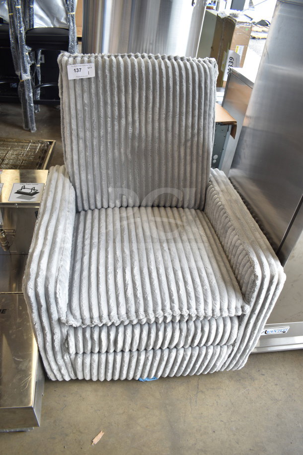 Gray arm chair with vertical pleated upholstery, modern design. Auction label indicates quantity: 1. Appears in good condition.
