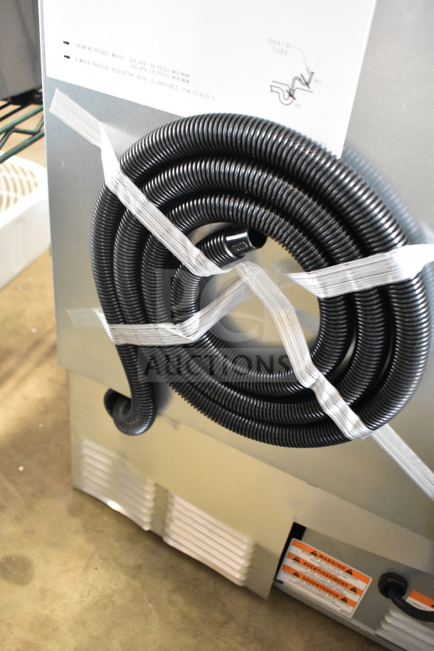 Manitowoc UDP0065A-161 ice machine, new with scratch and dent, featuring coiled hose and label with specs.