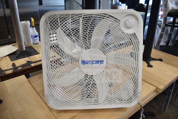 Hurricane HGC736501 box fan, white, 115 volts, 1 phase, shown on wooden surface. Brand logo visible on center.