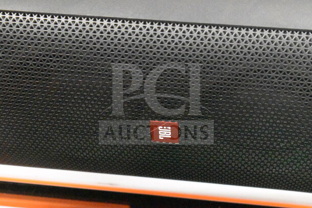 JBL speaker with black perforated grille, featuring a red JBL logo at the center.