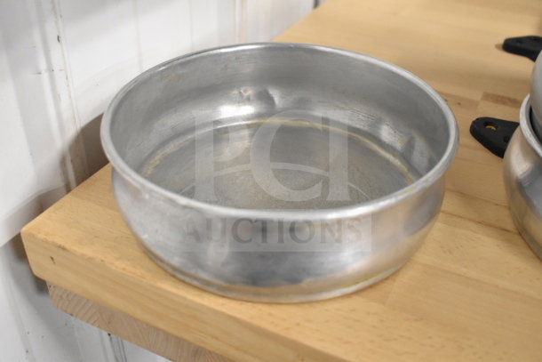 Round aluminum baking pan, lightly used, on a wooden shelf. Part of a lot of 22, ideal for bulk purchase.