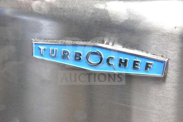 Silver Turbochef logo on the HhC2020 commercial electric conveyor oven, featuring blue background.