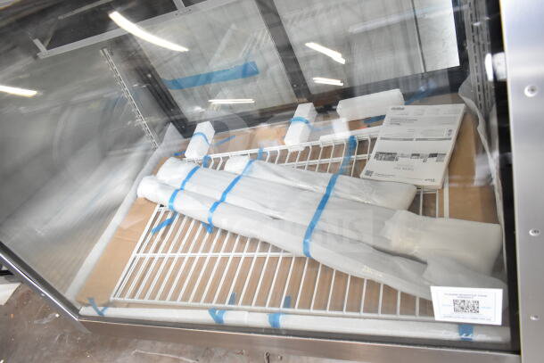 Brand new 2025 True TCGG-48-S-HC-LD deli case with curved glass, 48-1/4" length, 115V, 1 Phase. Visible packaging and manuals.