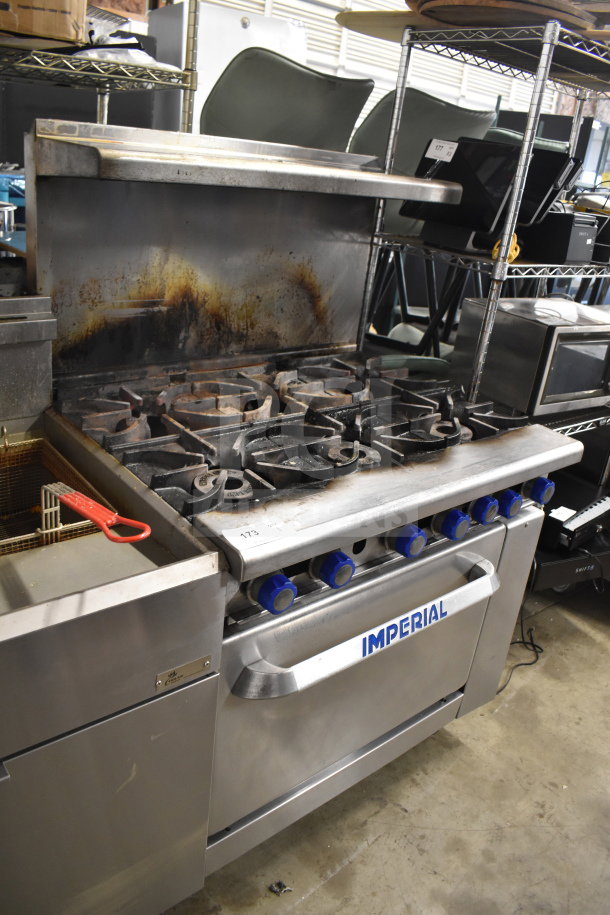 Imperial Commercial 6-burner gas range with oven, over shelf, and backsplash. Used condition, visible wear on surfaces.