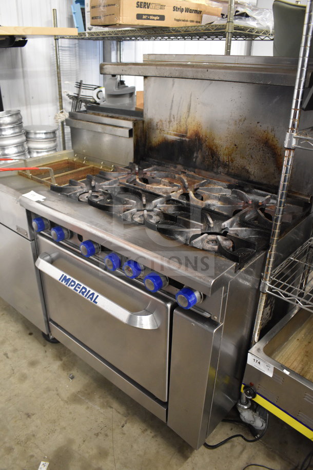 Imperial commercial 6-burner range with oven, over-shelf, and backsplash. Natural gas, visible wear, functional.