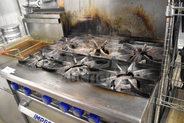 Imperial commercial natural gas 6-burner range with oven, over shelf, and backsplash, in used condition with visible wear.