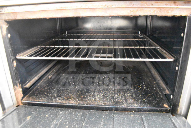 Imperial commercial natural gas 6-burner range oven interior, shows metal racks and signs of use, includes over shelf and back splash.