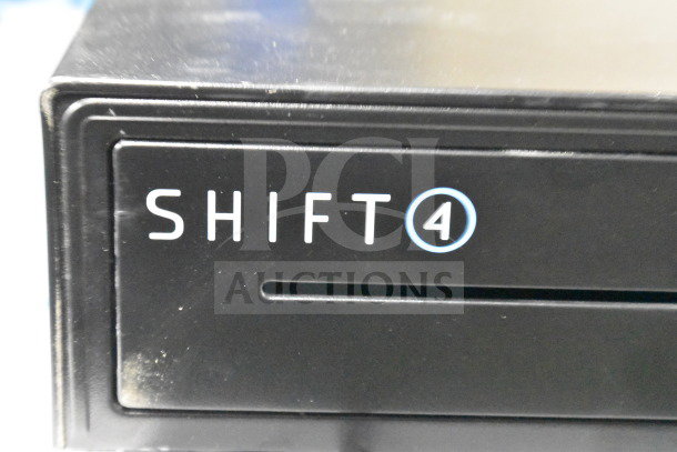 Shift4 cash drawer, black, featuring a coin slot. Model showcasing slight wear on the front panel.