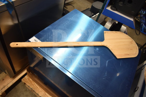 Wooden paddle on a metal surface, gently used, with visible grain. Includes bins, leg, and gas regulator. Auction lot of nine items.