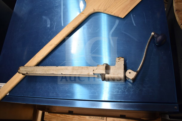A collection of items including a wooden paddle and metal component on a blue surface. Condition: used.