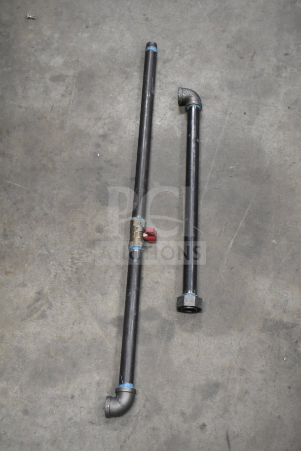 Four assorted metal pipes with connectors, valves, and elbow fittings on concrete floor, good condition.