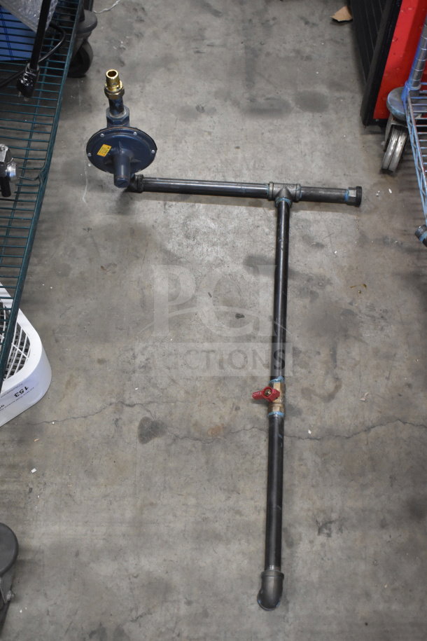Four various metal pipes connected with fittings, one featuring a valve and a gauge. Condition appears used. Suitable for industrial applications.