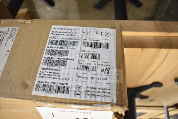 Cardboard box labeled "Shift 4" containing a 2024 APG cash drawer. Tags show model EKDS652-B410-A20, weight 18 lbs. Made in China.