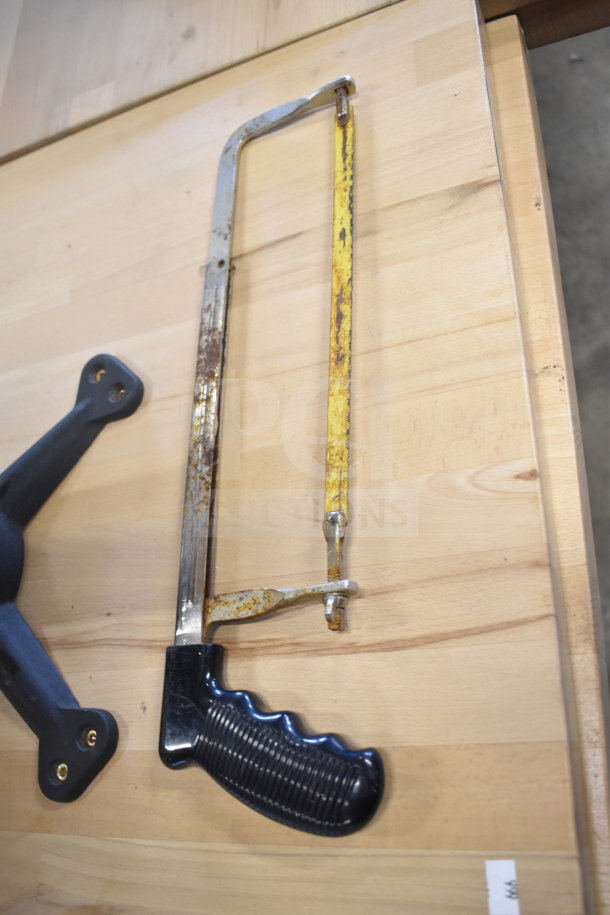 Rusty hand saw with a black ribbed handle on a wooden surface.