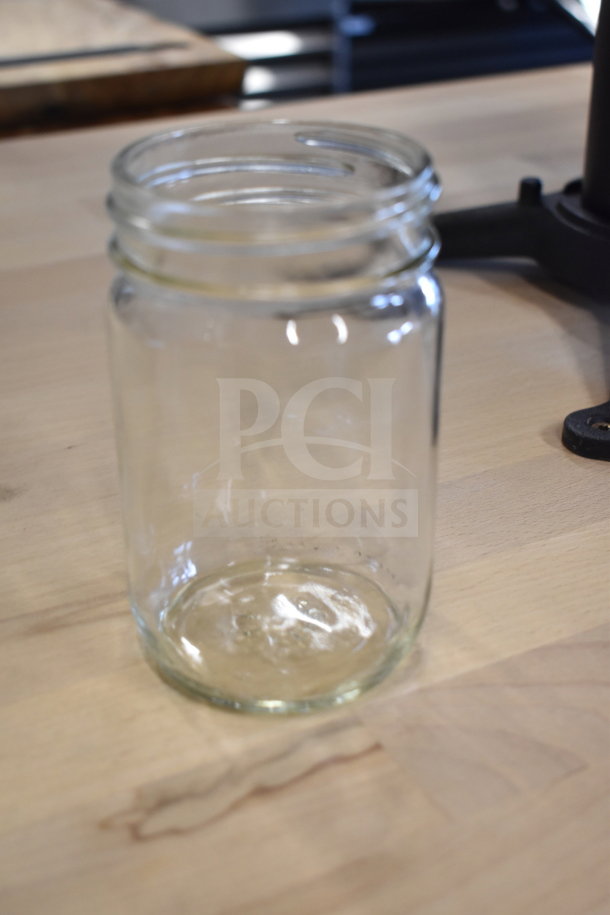 Clear glass jar on wooden surface, part of a scratch and dent auction set including cookware and grates.