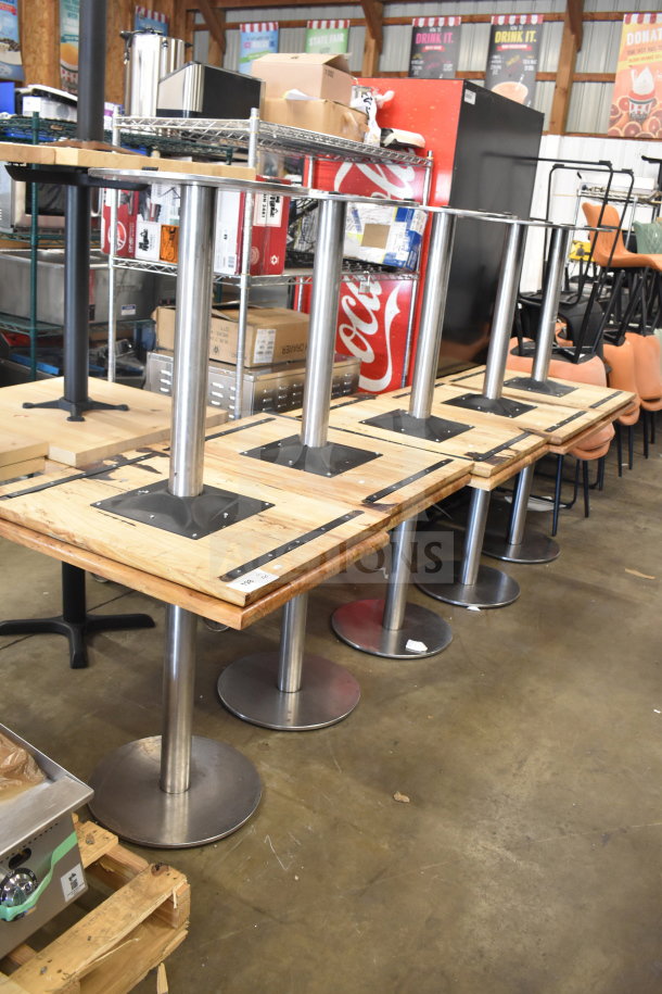 Set of 10 wooden dining tables with metal bases, auctioned as a lot. Tables show sturdy metal supports and natural wooden tops.