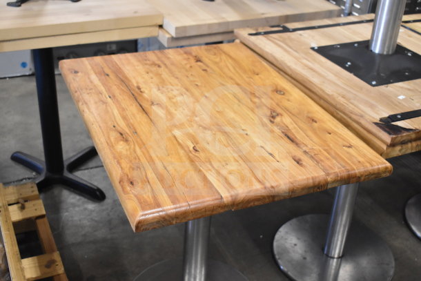 Wooden dining table with natural finish, metal base, sturdy construction, minor wear. Multiplies bid by ten times.