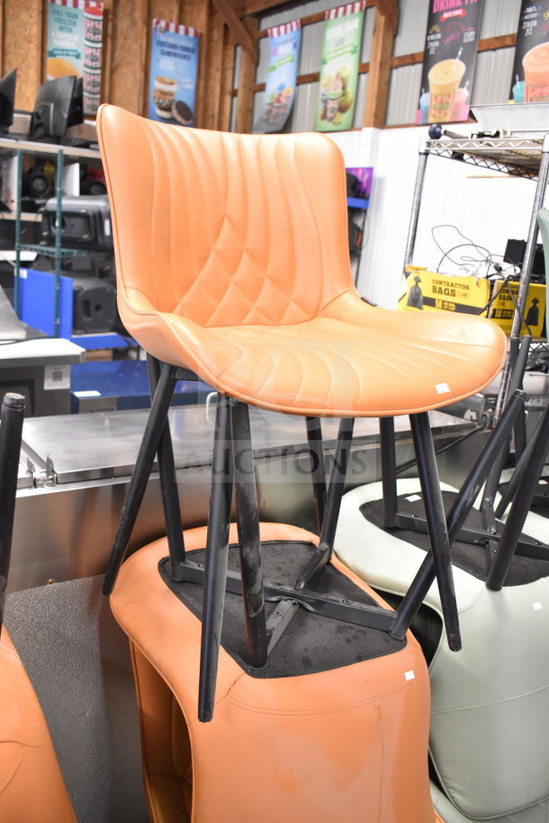 Orange tufted chair with black metal legs, part of a set of 20 assorted chairs including black and green. Good condition.