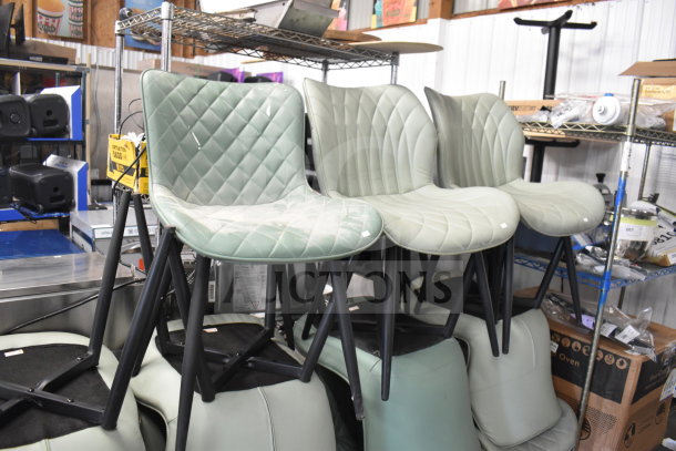 Various chairs in black, orange, and green colors stacked in a warehouse setting. Quilted pattern on seats, metal legs.