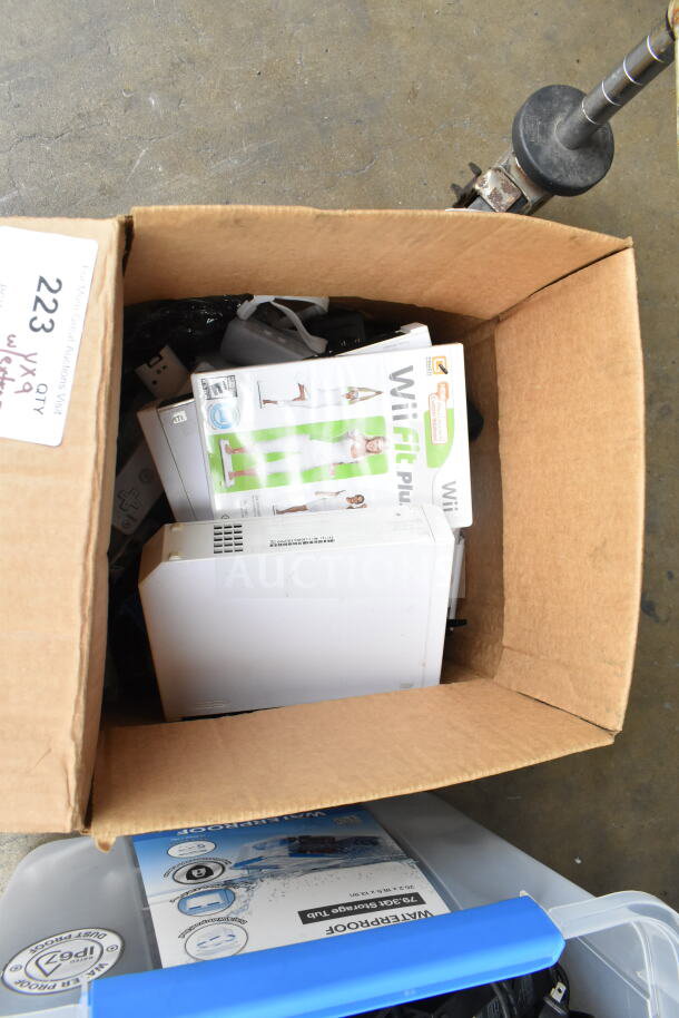 Cardboard box containing a Nintendo Wii console, Wii controllers, WiiFit Plus and WiiSports games. Box labeled "223."