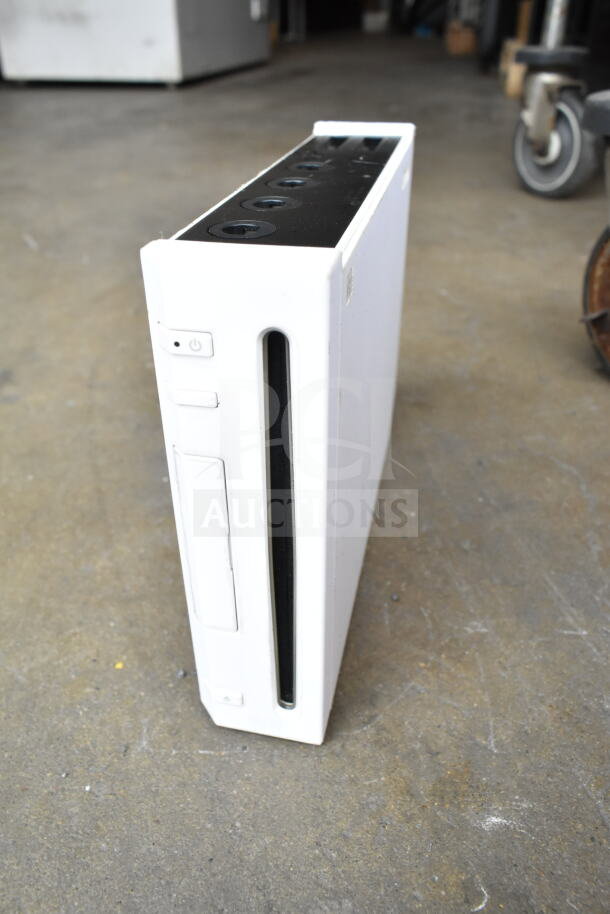Nintendo Wii console, white color, in used condition, with visible disc slot and buttons on top, part of a 9-item auction bundle.