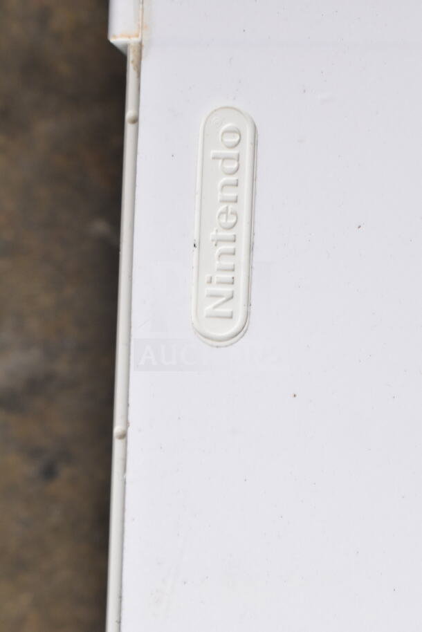 Nintendo Wii console in white, featuring Nintendo logo. Item includes Wii controllers and games, slight wear visible.