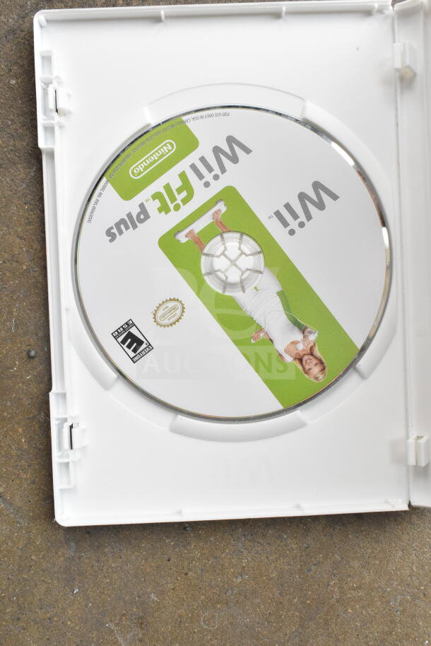 Wii Fit Plus game disc in open case, showing Nintendo and "E for Everyone" labels, appears in good condition.