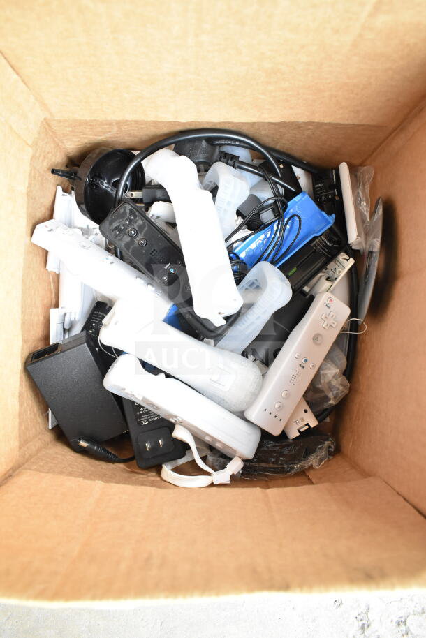 Cardboard box with various Nintendo Wii items including controllers, WiiFit Plus, WiiSports games, and accessories. Mixed condition.