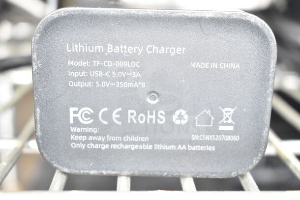 Clear poly bin with assorted cords and a lithium battery charger, model TF-CD-009LDC. Input: USB-C 5.0V 3A, output: 5.0V 350mA. Made in China.