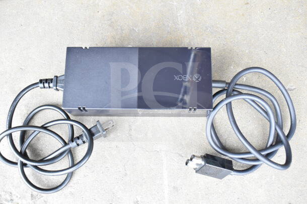 A collection of various cords and an Xbox battery charger in a clear poly bin. Perfect for tech enthusiasts.