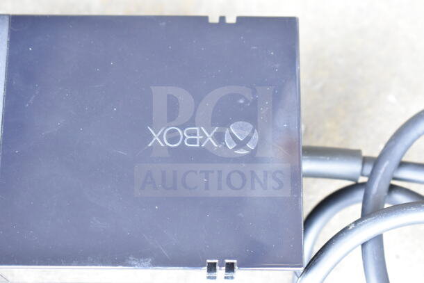 Lot of various cords and a battery charger in a clear poly bin; includes Xbox power supply with visible logo.