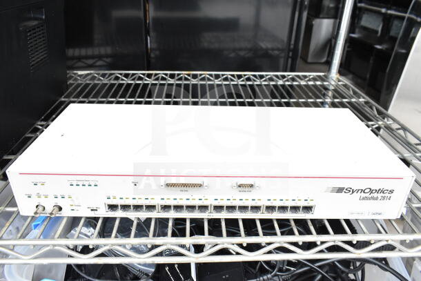 SynOptics LattisHub 2814 on metal shelf, features 16 Ethernet ports, visible power and function indicators, used condition.