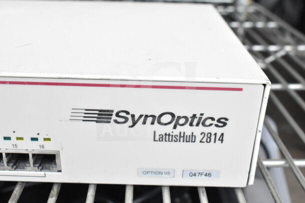 SynOptics LattisHub 2814 network hub in used condition, labeled "OPTION 05" and "047F46," metal body on wire rack.