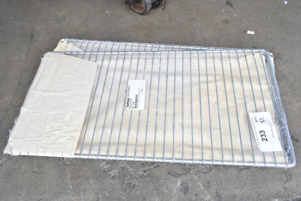 Two brand new Delfield 3977998 wire shelves, 19.38x25.25", in packaging. Some scratch and dent marks visible.