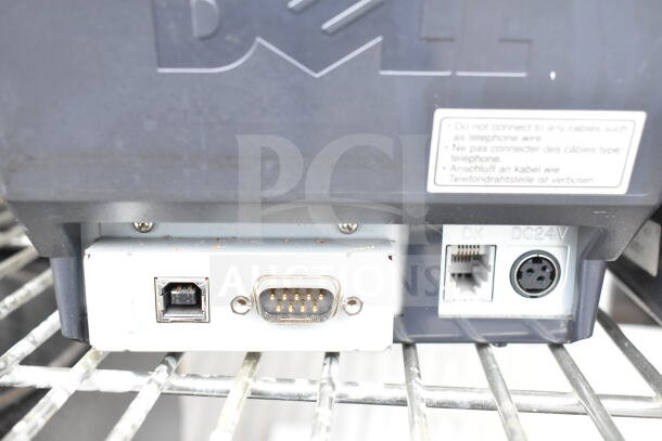 Dell receipt printer close-up showing various ports and a warning label.