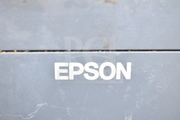 Epson receipt printer close-up showing brand logo on a gray surface. Part of a lot including POS monitors and Dell printer.