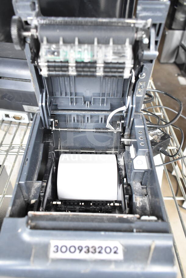 Open POS printer with visible paper roll and wiring, includes close-up of serial number 300933202.