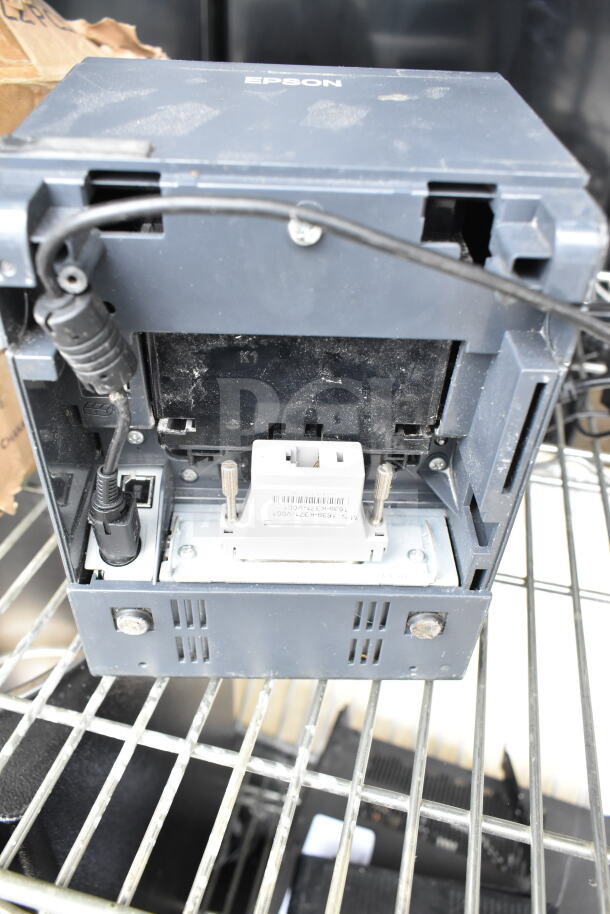 Epson receipt printer with visible connectors and slight surface wear, auction lot includes POS monitors and Dell printer.