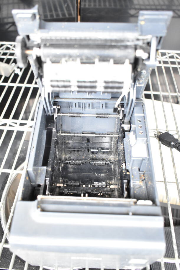Open Epson receipt printer on metal shelf, showing internal components; used condition.