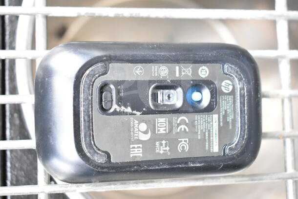 Close-up of an HP mouse with visible model and certification labels showing manufacturer details.
