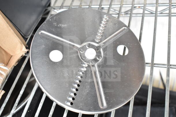 3 various items including a circular metal food processor blade with holes, in used condition, placed on a metal rack.