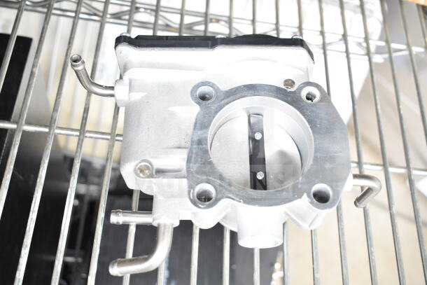 THBB1112-C throttle body, metallic finish, key component for engine airflow control, shown on metal rack.