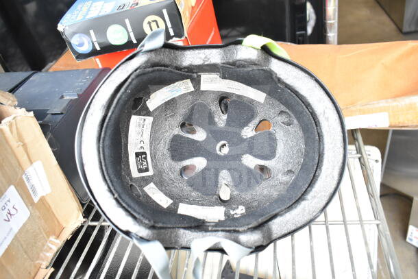 OnlyNY helmet interior showing size labels and ventilation. Includes USB dash cam, Roomba box nearby. Mixed condition.
